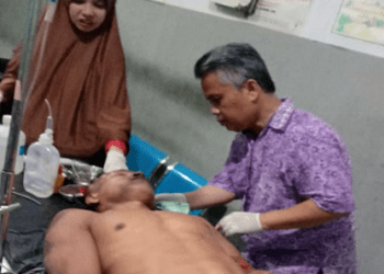 Adi Satria suami korban yang tewas tabrakan di Batubara saat mendapat perawatan medis.