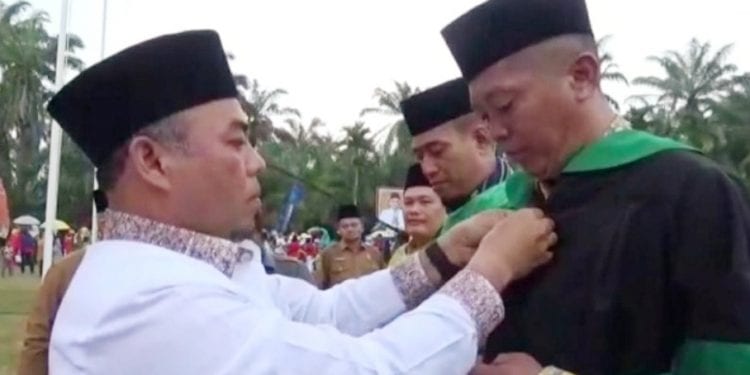 Bupati Labuhanbatu H Andi Suhaimi Dalimunthe ST MT (kiri) saat memakaikan toga kepada ketua Dewan Hakim MTQH Ke-49 Tingkat Kabupaten Labuhanbatu H Khairul Dalimunthe SAg (kanan).