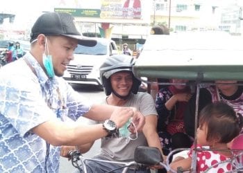 Ketua KPU Labuhanbatu Wahyudi saat memberikan masker kepada warga yang melintas.