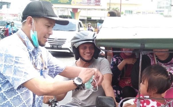 Ketua KPU Labuhanbatu Wahyudi saat memberikan masker kepada warga yang melintas.
