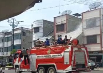 Petugas menyemprotkan desinfektan di jalan Kota Rantauprapat dengan menggunakan mobil Damkar