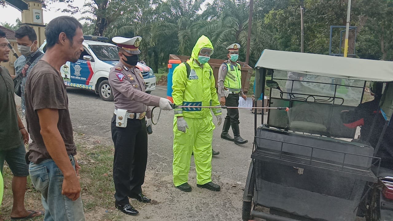 Personel Satlantas Polres Sergai menyemprot desinfektan pada pengendara di jalinsum.