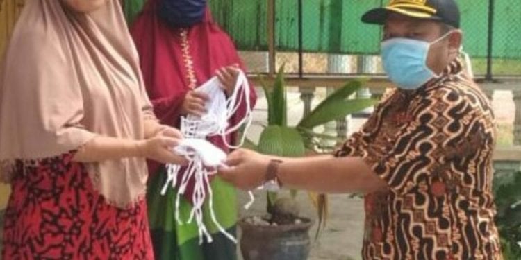 Kades Kampung Padang saat membagikan masker ke warga.