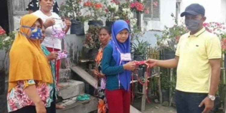 Kades Negeri lama Supriono saat memberikan masker kepada sejumlah warga.