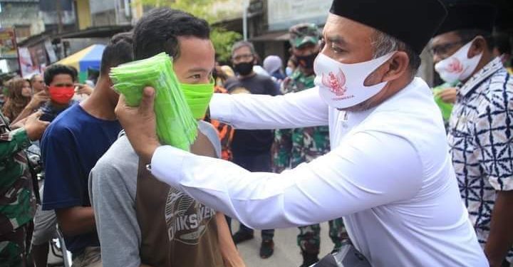 Andi Suhaimi saat memakaikan masker kepada warga.