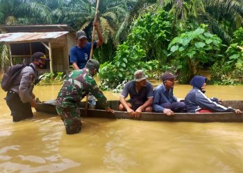 (Richad Silaban/taslabnews) Petugas Polsek Kualuh Hulu dan Koramil 01/AK mengevakuasi warga yang rumahnya terendam banjir