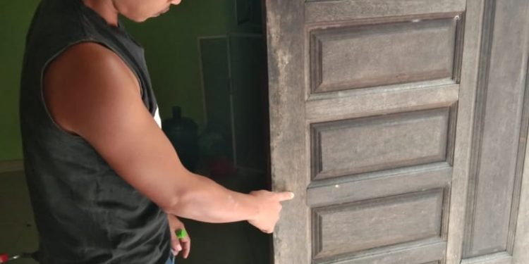 Surya menunjukkan pintu belakang rumahnya yang dicungkil maling.