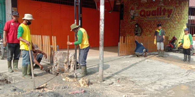 Petugas kebersihan Dinas PUPR Asahan saat membersihkan saluran parit di depan tempat usaha kuliner Quaility Fried Chicken Kota Kisaran.