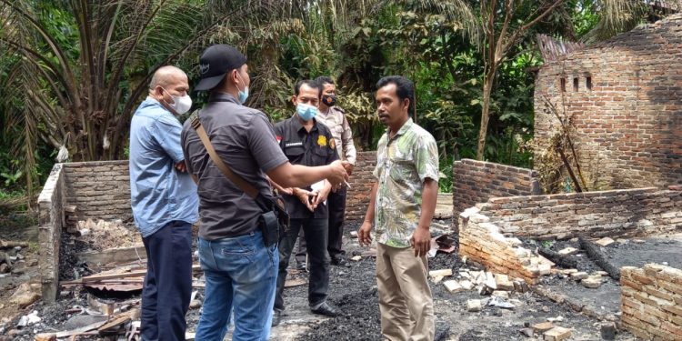 Kanit Reskrim Kualuh Hulu, Ipda Eko Sanjaya bersama Kades Siamporik, Sahat Maruli Sianipar sedang melihat puing kebakaran.
teks/foto: richard silaban