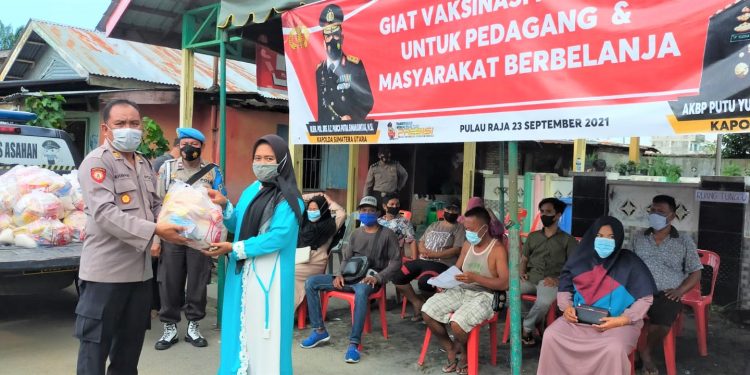 Kapolsek Pulau Raja AKP. Maralidang Harahap saat pelaksanaan vaksinasi dan pemberian sembako.