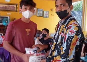 Ketua PKN Labuhanbatu Ricky saat memberikan satu karung beras kepada warga yang mengikuti vaksinasi massal.