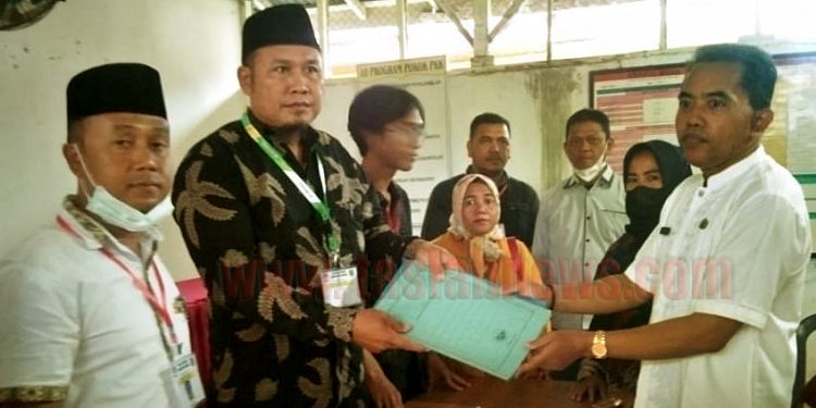 Suyatno (paling kanan) menyerahkan berkas pendaftaran kepada Ketua Panitia Pilkades Sei Beluru, Bukhori.