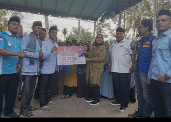 Hj Delmeria Sikumbang menyerahkan bantuan modal usaha budi daya ikan lele kepada Ketua DPD BKPRMI Tapteng Erman Sakti Hutabarat.