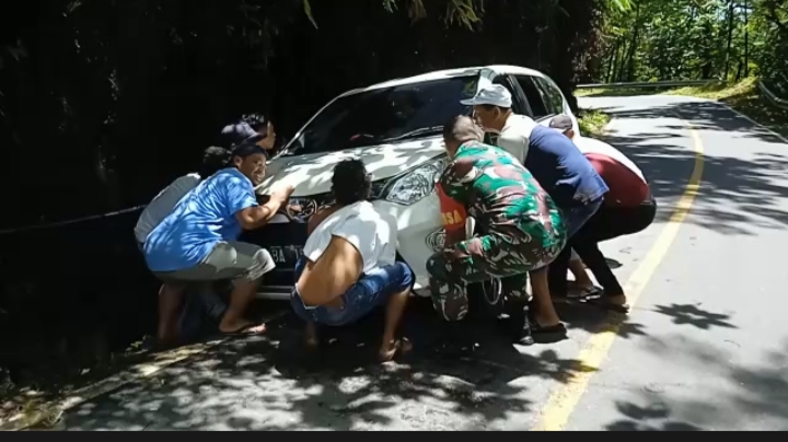 (TASLABNEWS/Rey Simorangkir)Babinsa Koramil 05/Kolang, Serda Benni Sitompul bersama warga mengevakuasi mobil Calya yang terperosok ke parit di Jalan Sibolga-Tarutung Km 7 Desa Simaninggir, Kabupaten Tapteng.