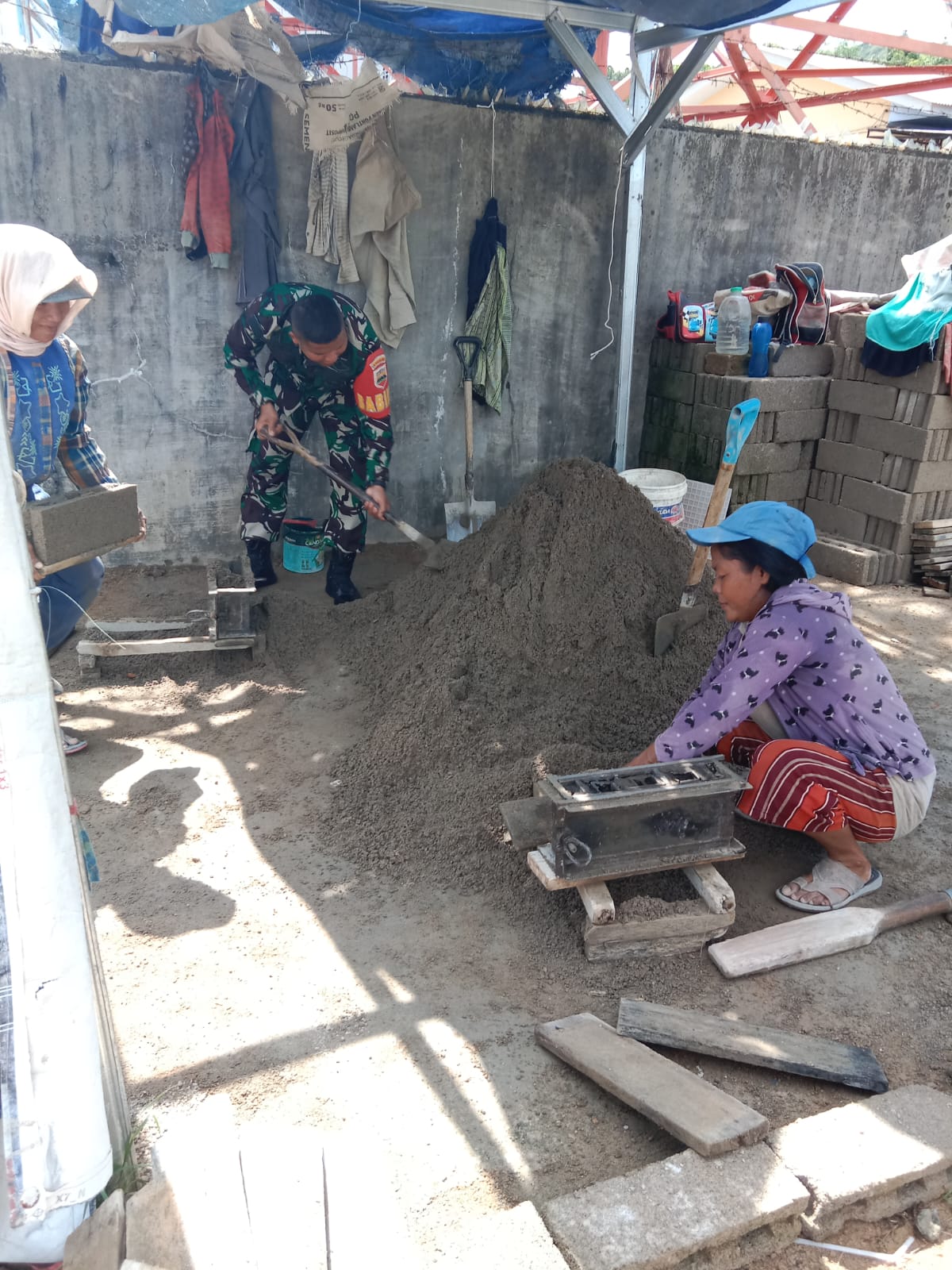(Rey Simorangkir/TASLABNEWS)Babinsa Koramil 05/Kolang, Serda Benni Sitompul membantu mencetak batako di Desa Rampah, Kabupaten Tapteng, Selasa (11/04/2023). 