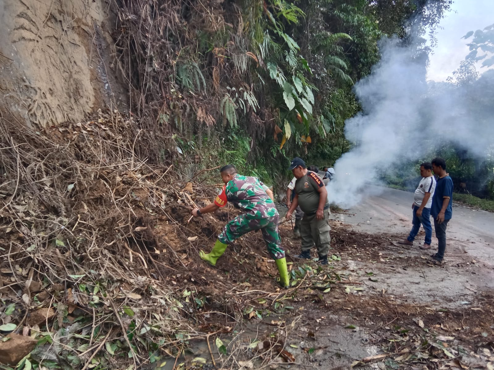 Babinsa Koramil 05/Kolang, Serda Benni Sitompul bersama warga bergotong royong membersihkan semak belukar, di Jalan lintas Sibolga- Tarutung Desa Simaninggir, Tapteng. 