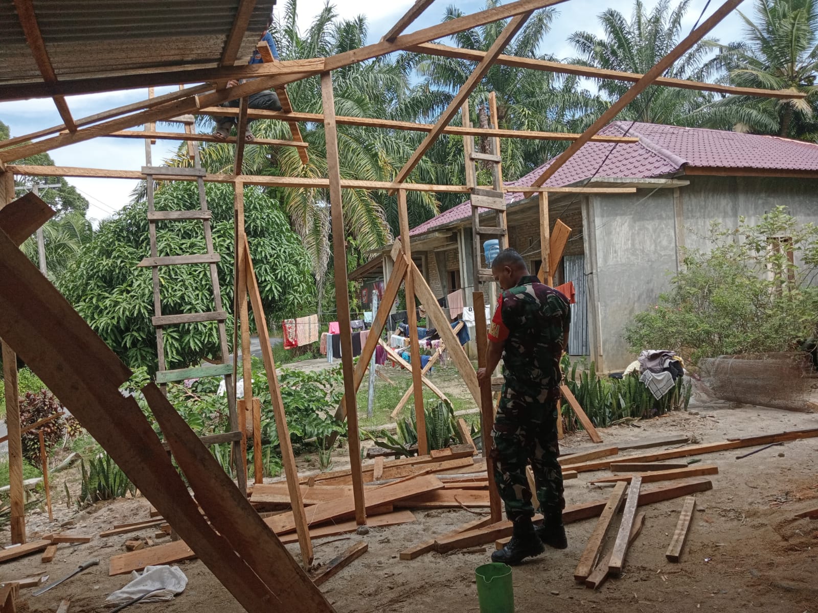 Babinsa Koramil 05/Kolang, Serda Kepler Situmorang membantu warga membangun rumah tempat tinggal, di Desa Simarpinggan, Kabupaten Tapteng. 