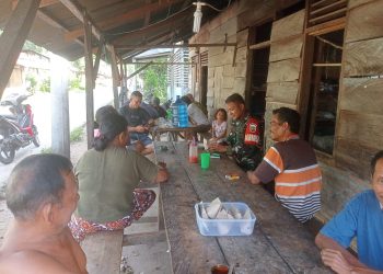 Babinsa Koramil 05/Kolang, Serda Kepler Situmorang saling bertukar pikiran dan bersendau gurau dengan warga di Desa Simarpinggan, Kabupaten Tapteng.