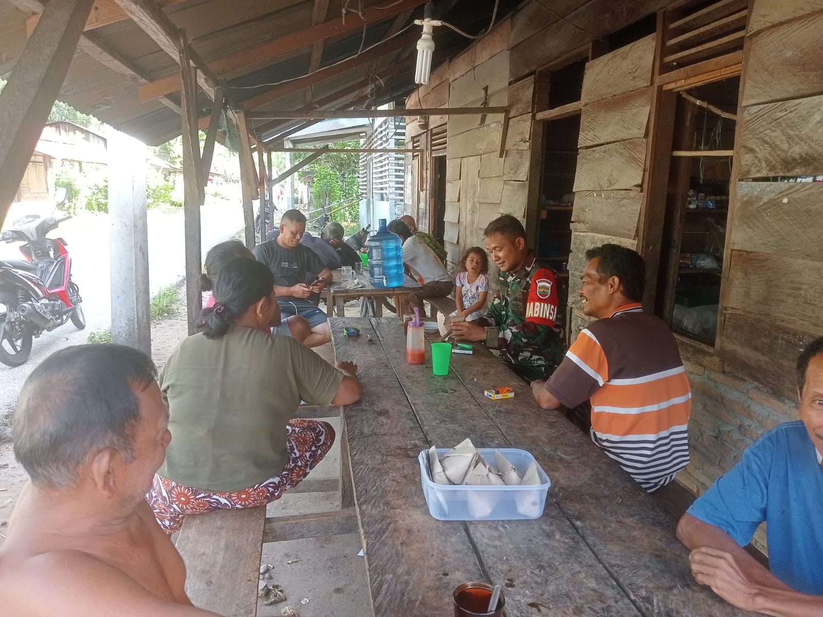 Babinsa Koramil 05/Kolang, Serda Kepler Situmorang saling bertukar pikiran dan bersendau gurau dengan warga di Desa Simarpinggan, Kabupaten Tapteng.