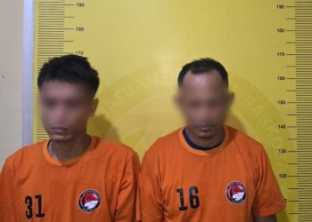 Dua tersangka saat di kantor polisi.