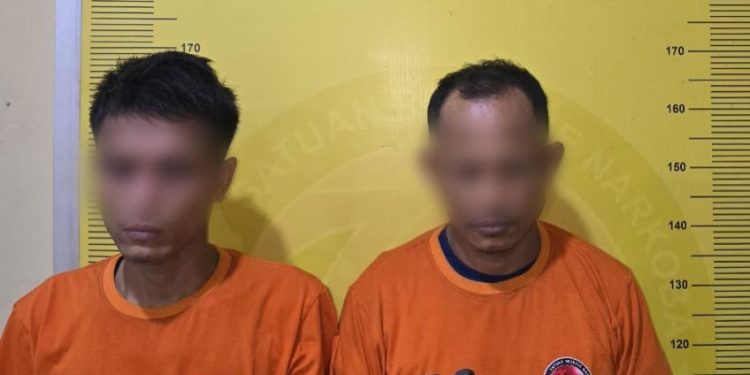 Dua tersangka saat di kantor polisi.