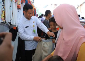 H Samsul Tanjung menawarkan celana kepada anak yatim.