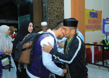 Wakil Bupati Labura, H. Samsul Tanjung (pakai peci), memeluk Bupati Labura, H. Hendriyanto Sitorus, setibanya di Kualanamu, usai menunaikan rukun Islam kelima. 