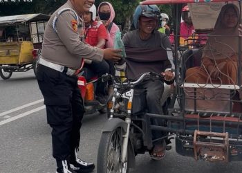 Personel polisi saat membagikan nasi kotak kepada abang becak saat melintas di depan Kantor Polres Labuhanbatu.