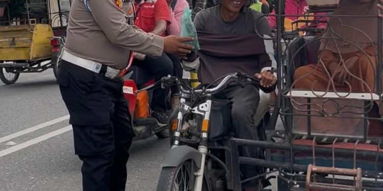 Personel polisi saat membagikan nasi kotak kepada abang becak saat melintas di depan Kantor Polres Labuhanbatu.