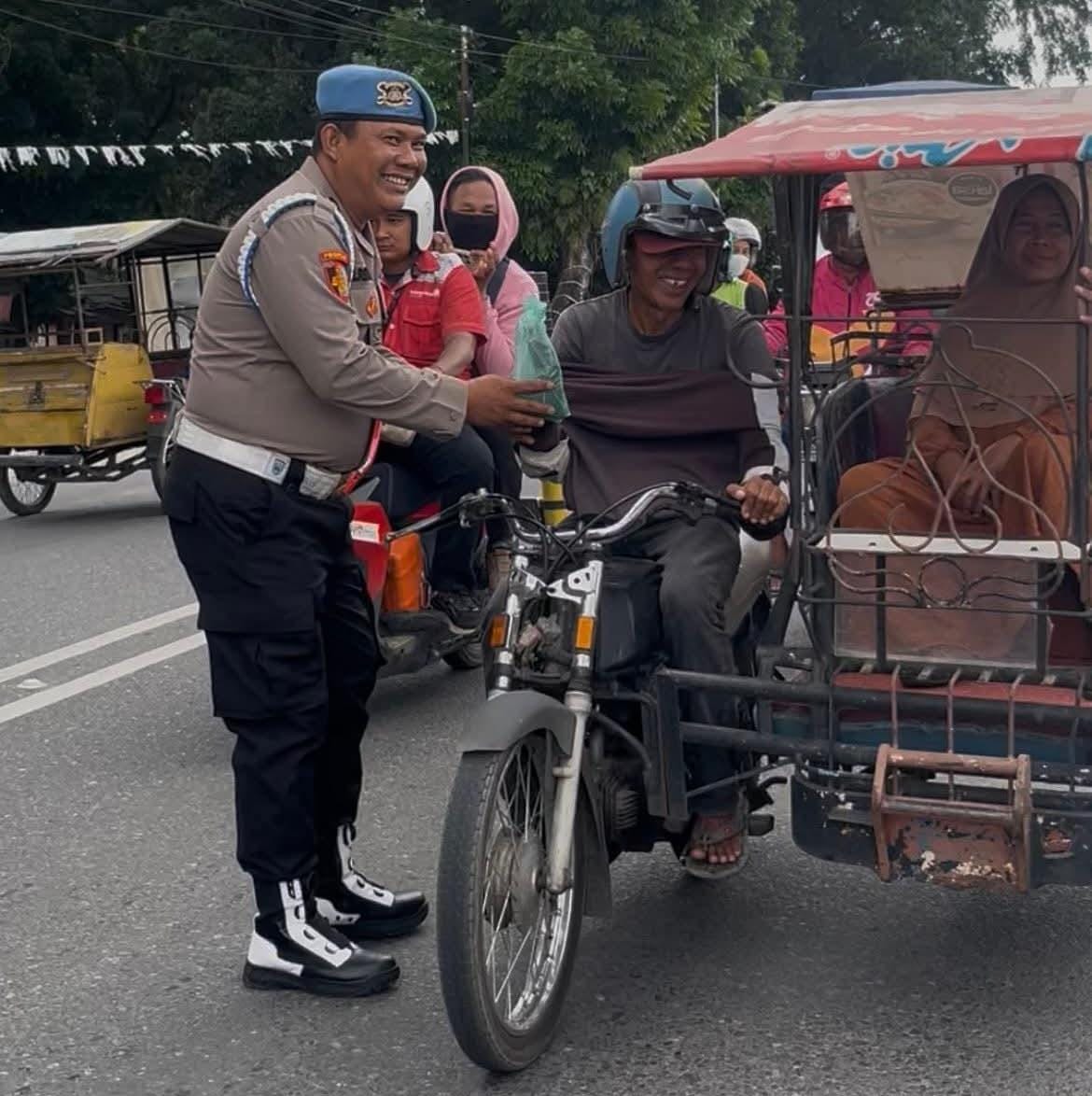 Personel polisi saat membagikan nasi kotak kepada abang becak saat melintas di depan Kantor Polres Labuhanbatu.