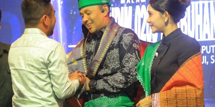 H . Samsul Tanjung menyerahkan kain songket kepada Letnan Kolonel Kav Hanung Kaptiaj.