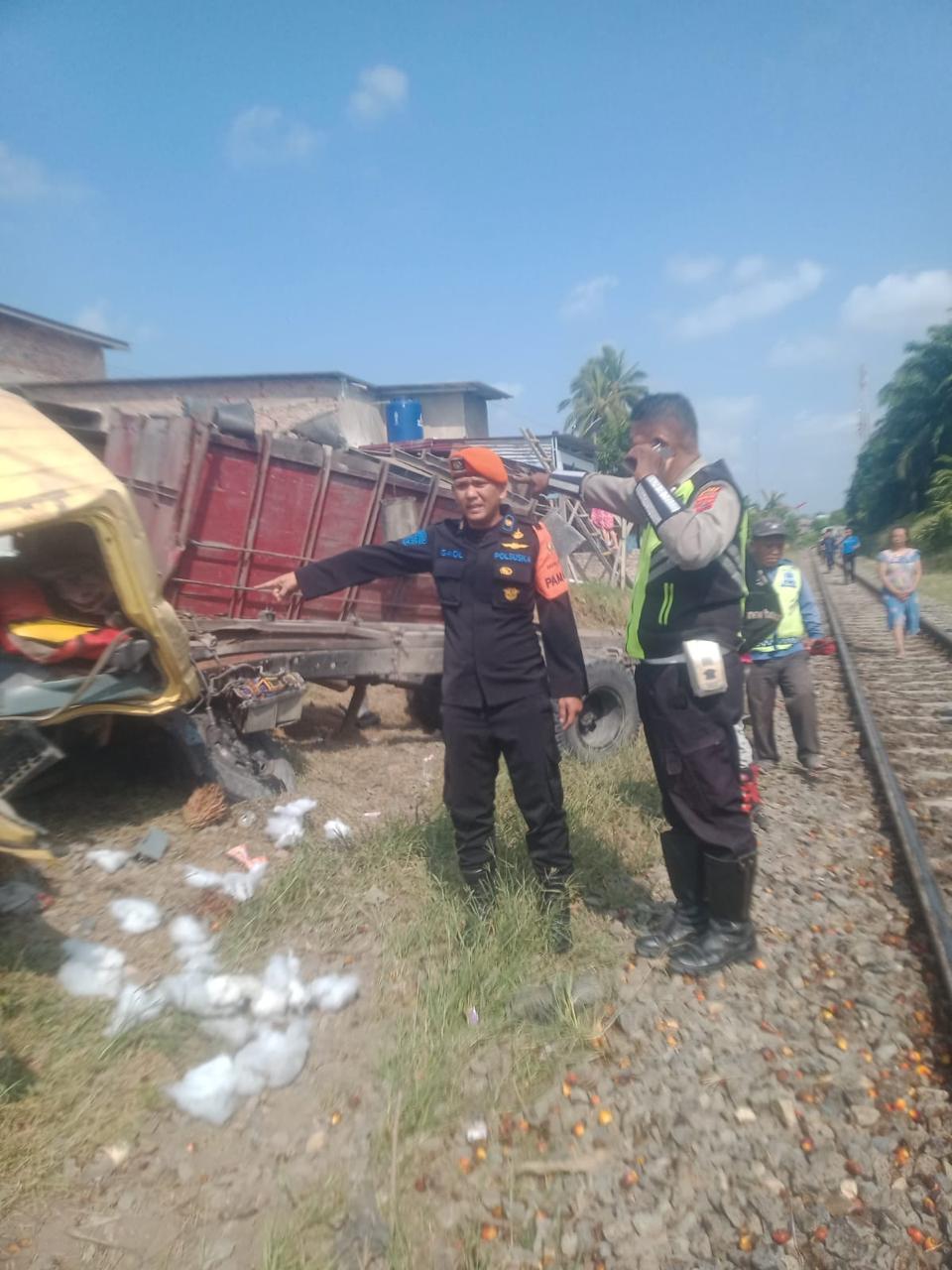 Warga berkerumun di lokasi truk yang tertabrak kereta api. 