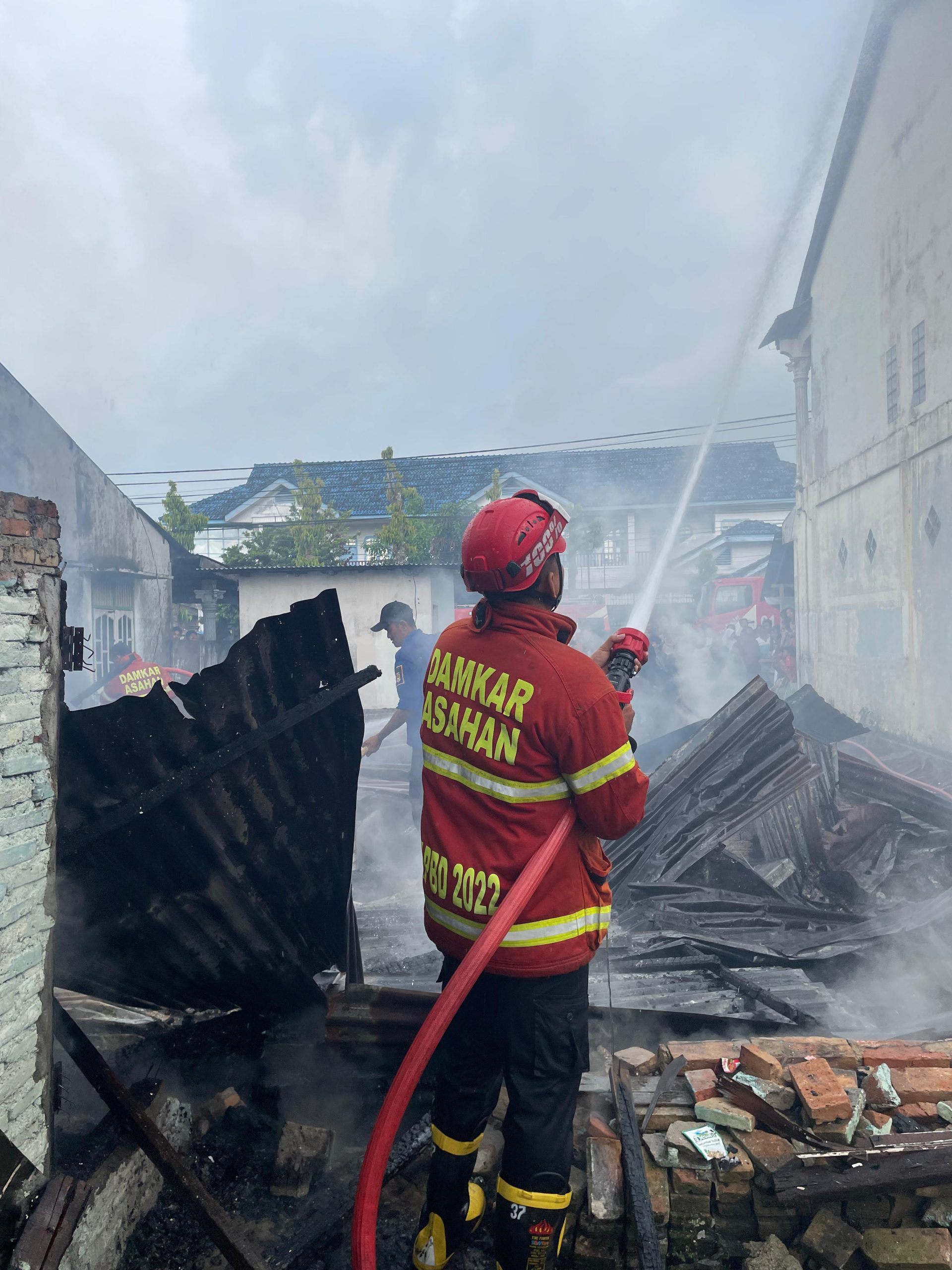 Petugas pemadam kebakaran menjinakkan api yang membakar rumah warga. 
